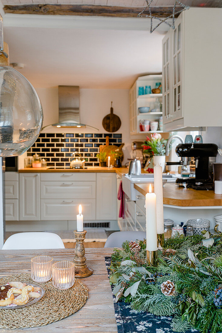 Candles on table and view into open-plan country-house-style kitchen