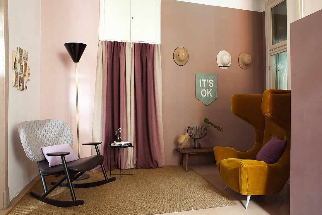 Wohnraum in Rosatönen mit ockerfarbenem Vintage-Ohrensessel und Schaukelstuhl