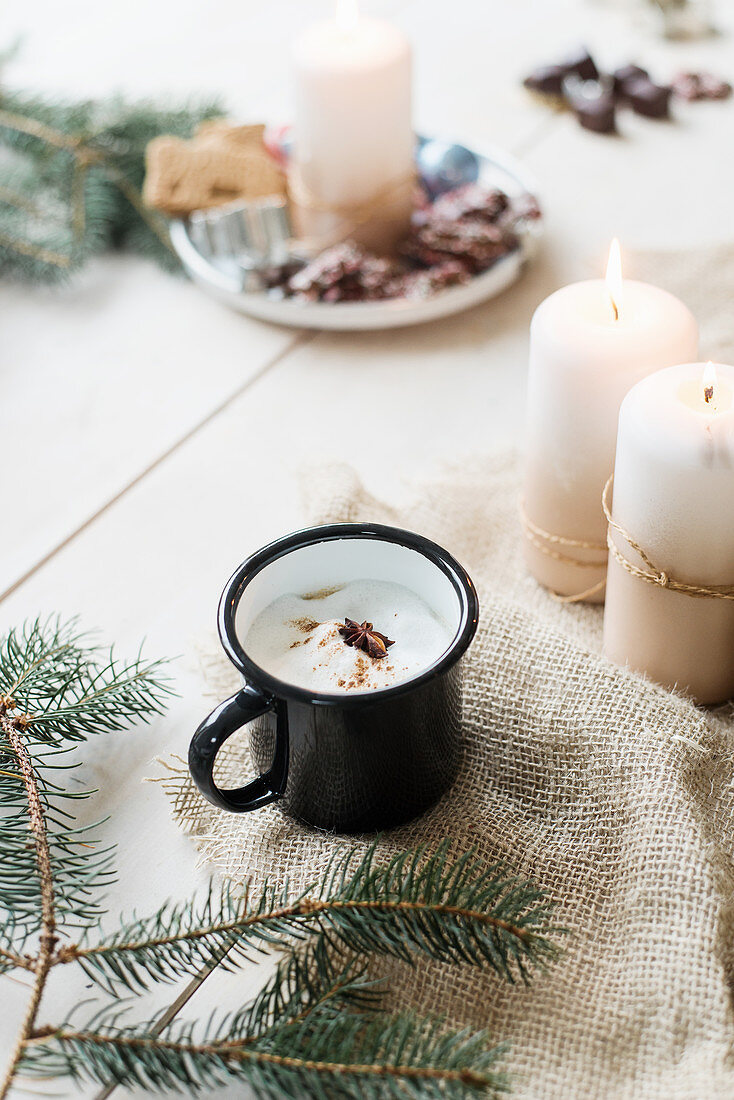 Hot drink in enamel mug anc candles on hessian fabric