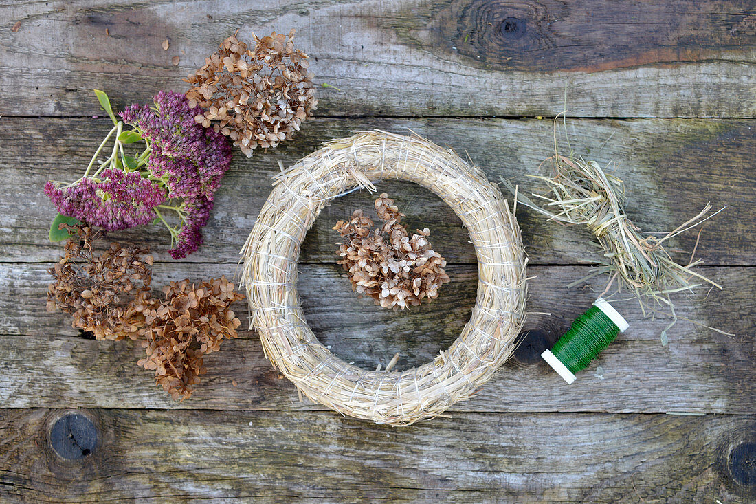 materials for an autumn wreath: dried hydrangea flowers, sedum plant, straw horns, hay, and binding wire