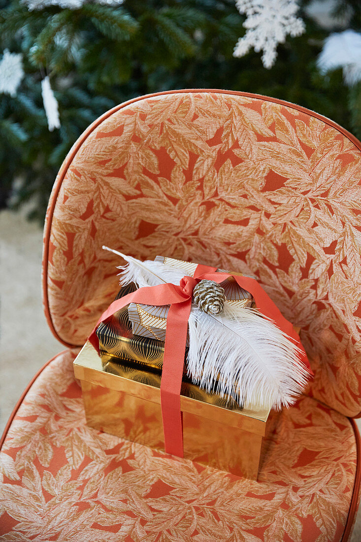 Wrapped presents decorated with ribbon, feathers and pine cones on easy chair