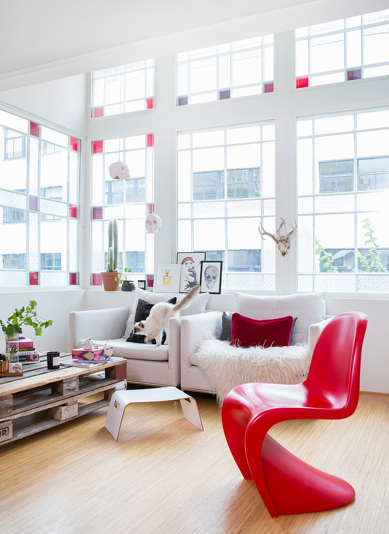 Roter Designerstuhl im Wohnzimmerm mit Buntglasfenstern