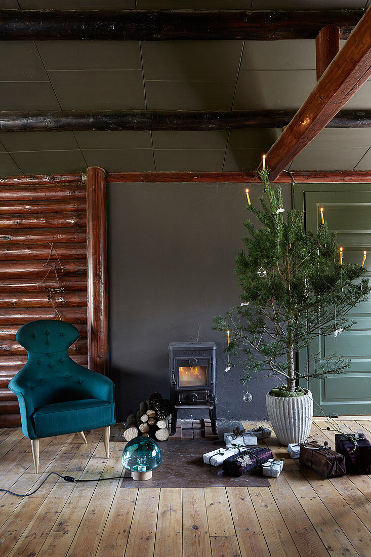 Geschmückter Baum, Weihnachtsgeschenke und Sessel vor Kaminofen