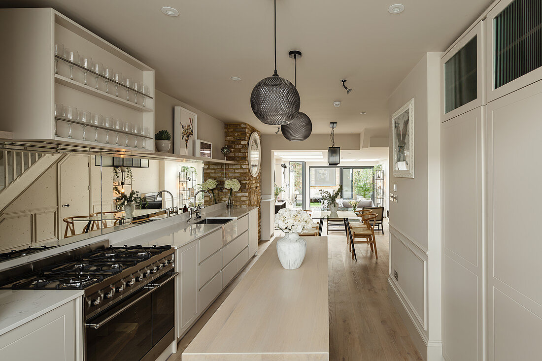 Weiße Küche mit schmaler Kücheninsel in langgestrecktem offenen Wohnraum
