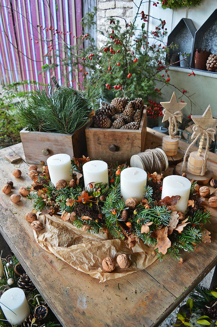 Ländliche Adventsdekoration mit Kerzen im länglichen Adventskranz, Schubladen mit Zapfen und Zweigen
