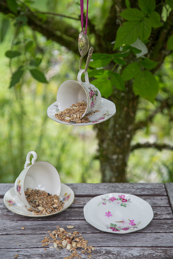 Bird feeder made from old teacup and saucer hung from bent spoon