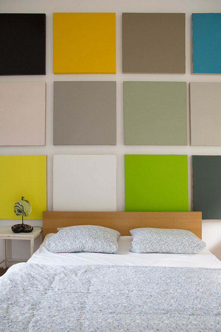 Wall decorated with multicoloured squares above bed in bedroom