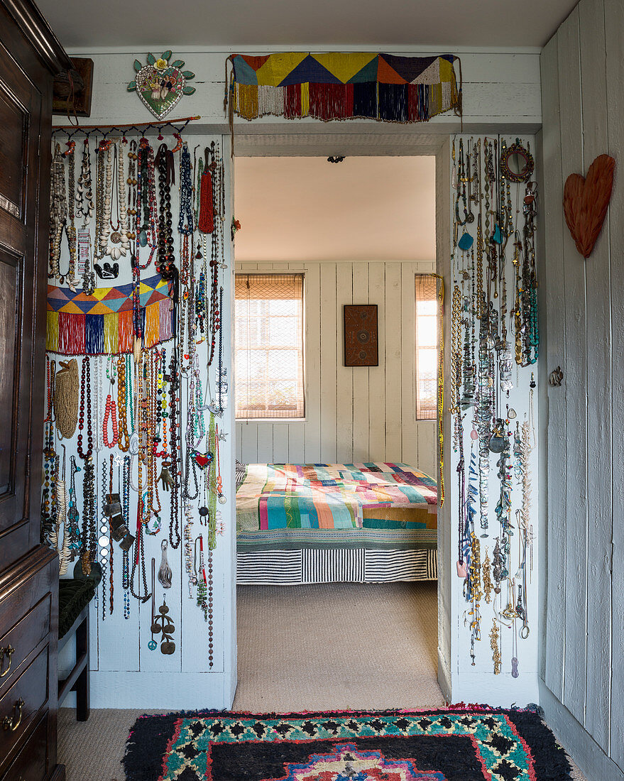 Collection of necklaces hanging on walls flanking doorway leading into bedroom
