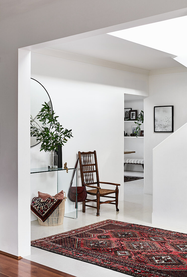 Blick auf Stuhl und Glaskonsole in weißem Treppenraum