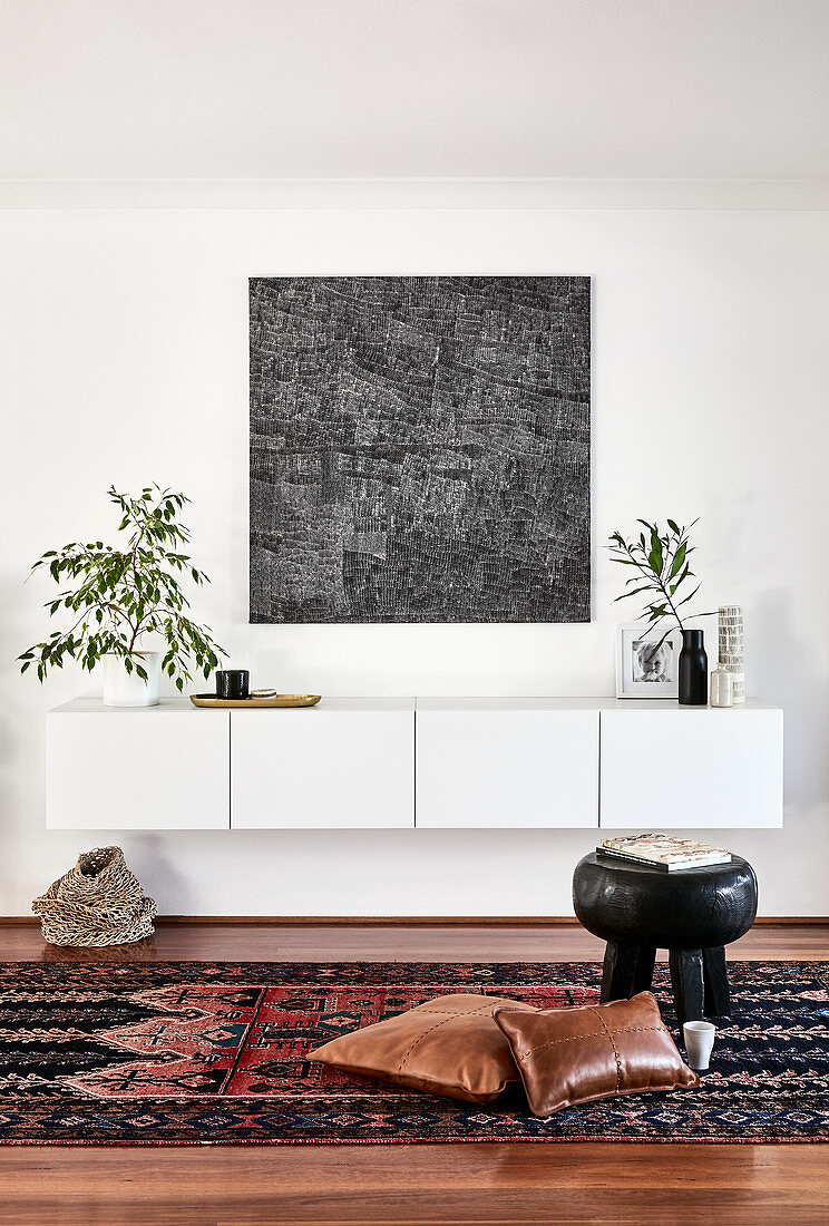 Weißes Hängeboard, moderne Kunst und Zimmerpflanzen im Wohnzimmer
