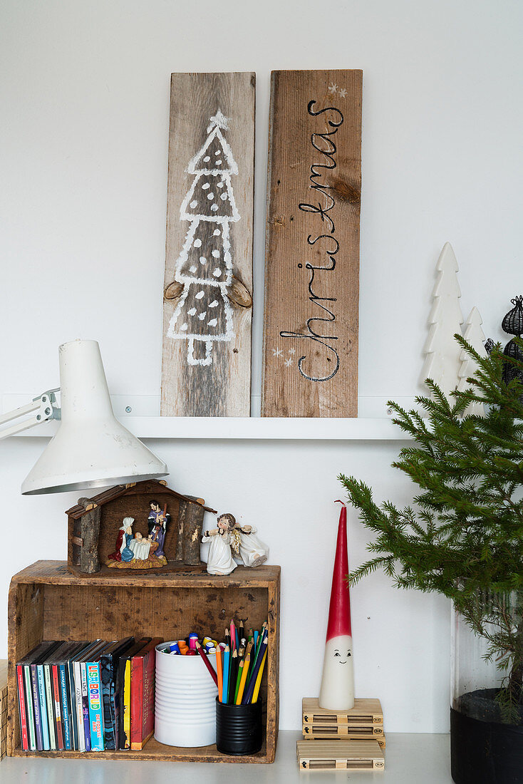 Christmas pictures drawn on wooden boards above nativity set on wooden crate