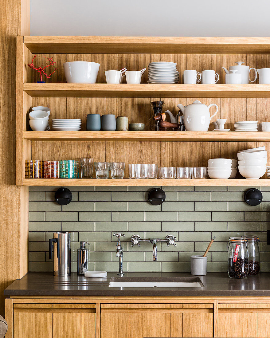 Crockery and glasses on shelves above sink in modern kitchen