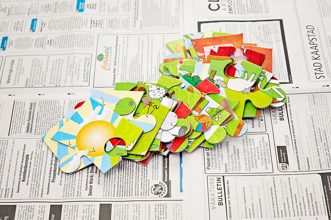 Große Kinderpuzzleteile auf Zeitungspapier ausgebreitet