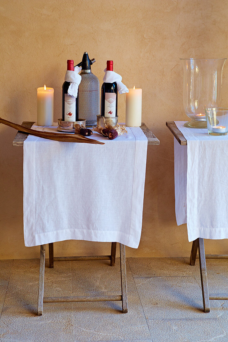 White cloths, wine bottles and candles on two folding tables