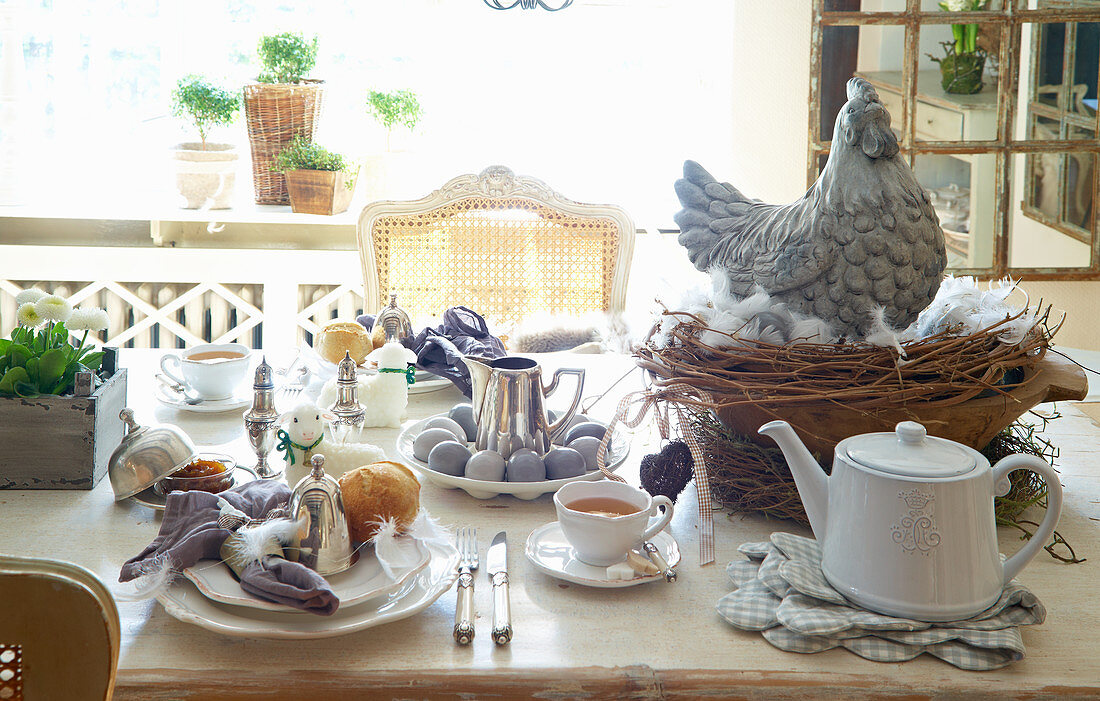 Gedeckter Tisch fürs Osterfrühstück mit Deko-Huhn auf Nest