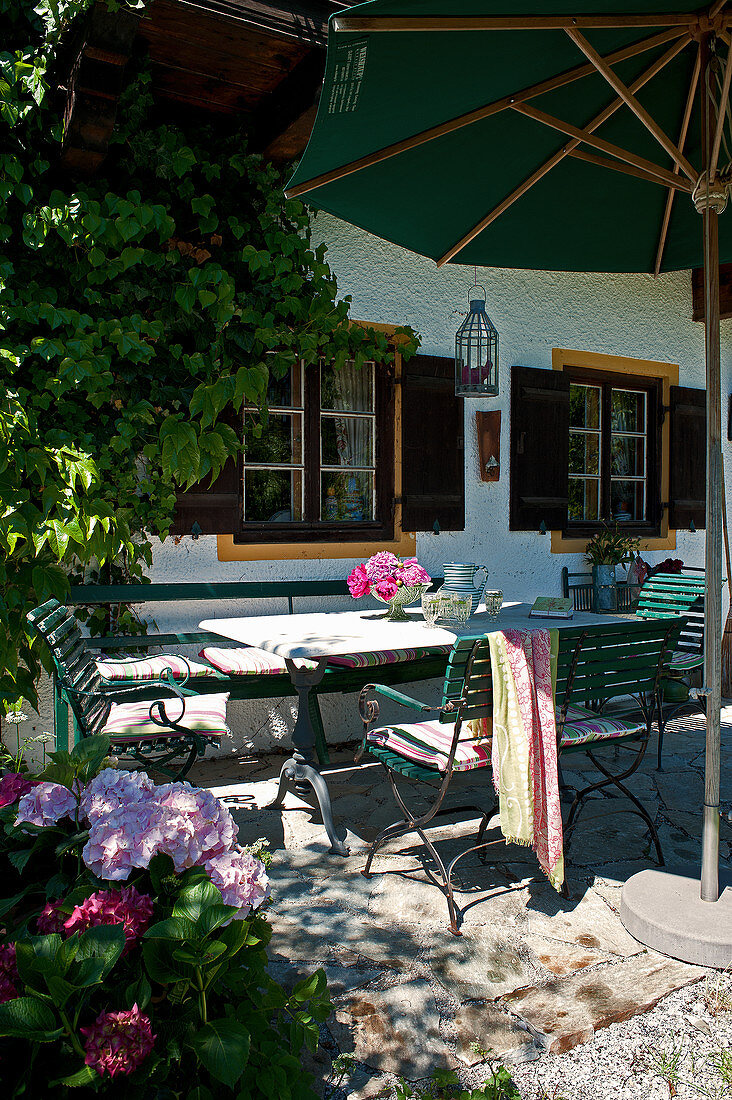 Gartentisch mit Stühlen unter Sonnenschirm auf der Terrasse
