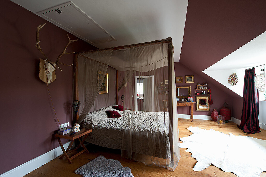 Himmelbett im Schlafzimmer mit auberginefarbenen Wänden