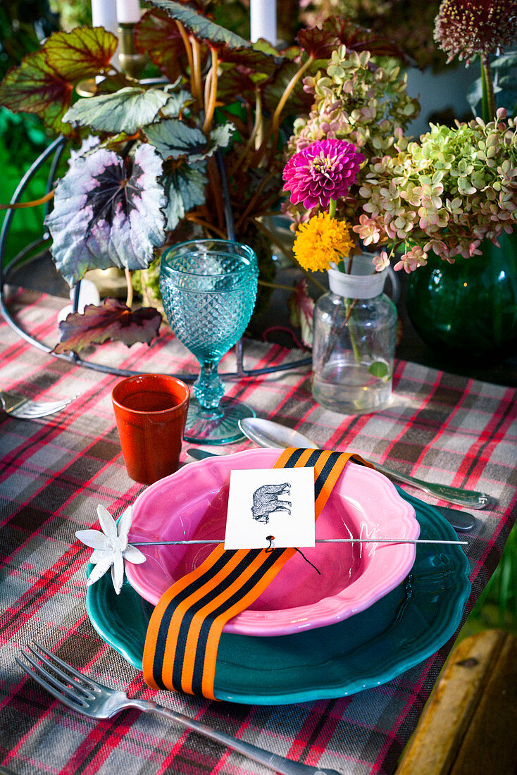 Farbenfrohes Tischgedeck dekoriert mit Scheifenband, Kärtchen und Blüte