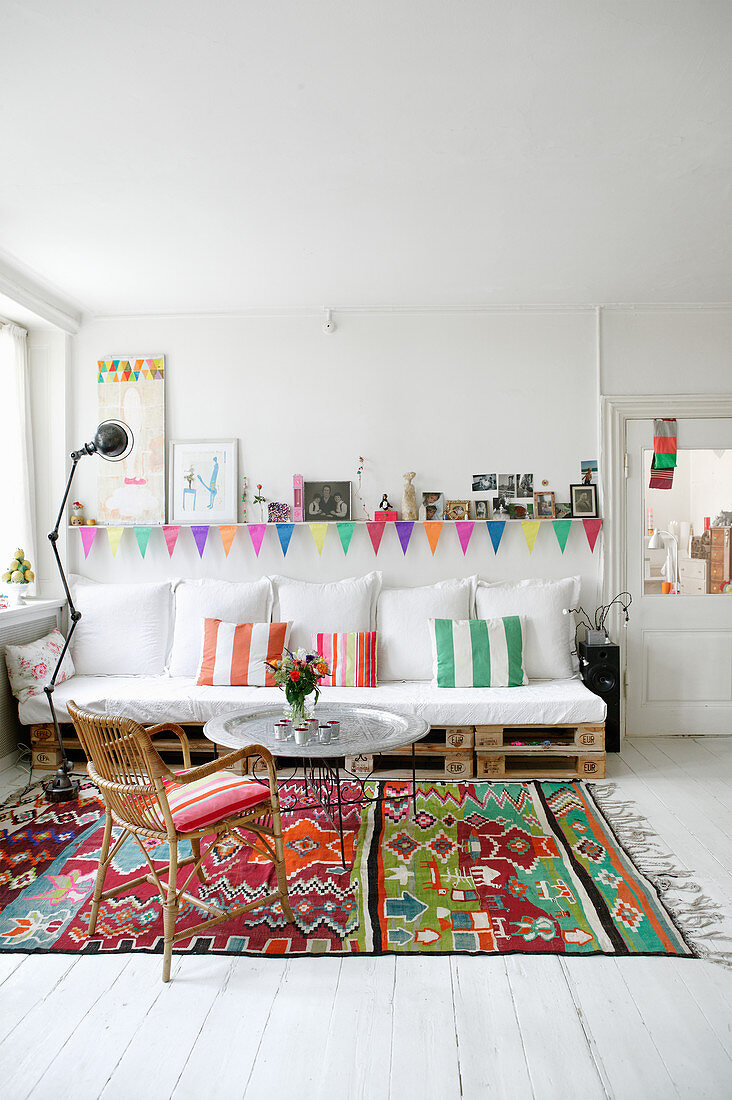 Sofa aus Paletten im Wohnzimmer mit weißem Boden und Farbakzenten