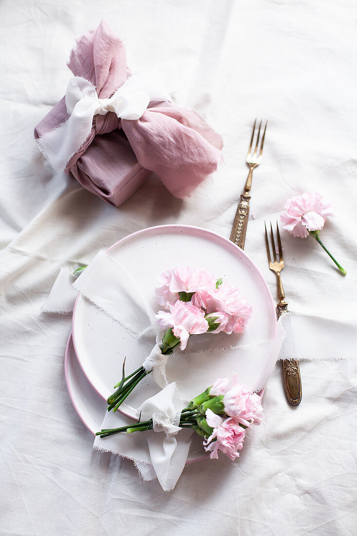 Posies of pink carnations tied with ribbons on plates