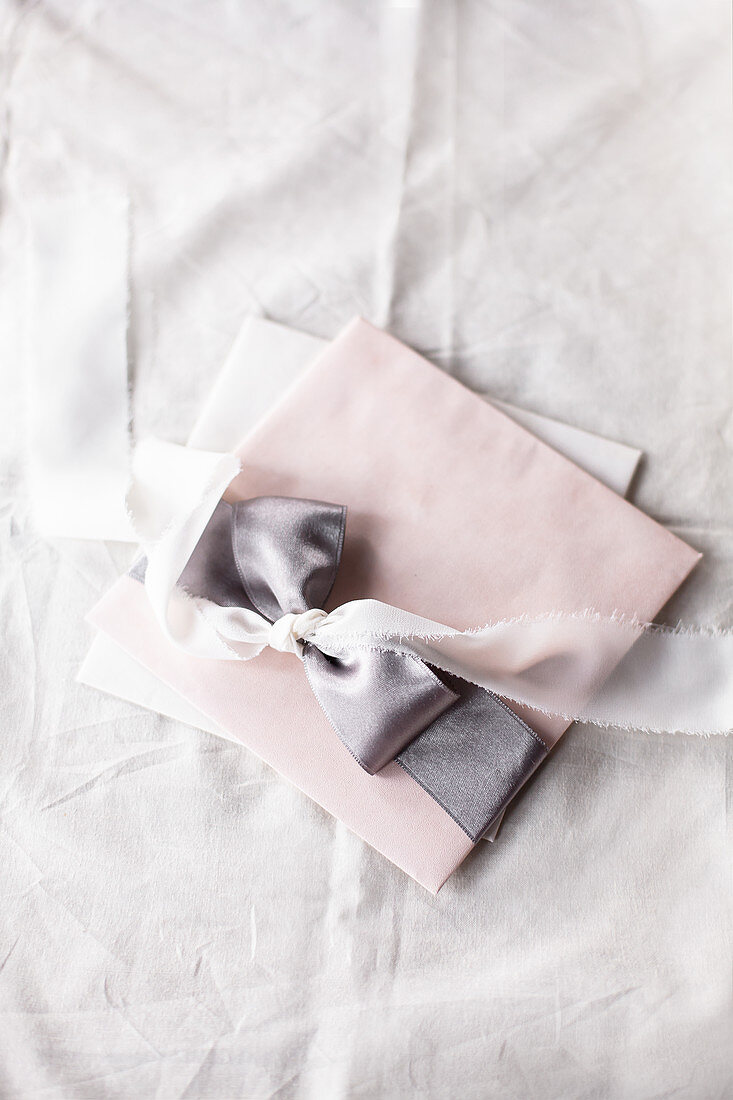 Pastel arrangement: envelopes tied with satin ribbons on fabric
