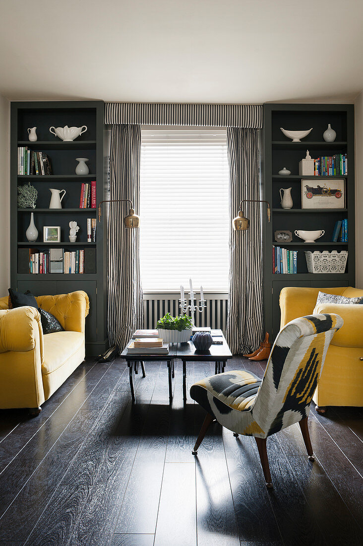 Two yellow sofas facing one another in symmetrical living room in shades of grey