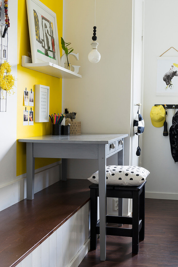 Grey desk on bench against yellow wall