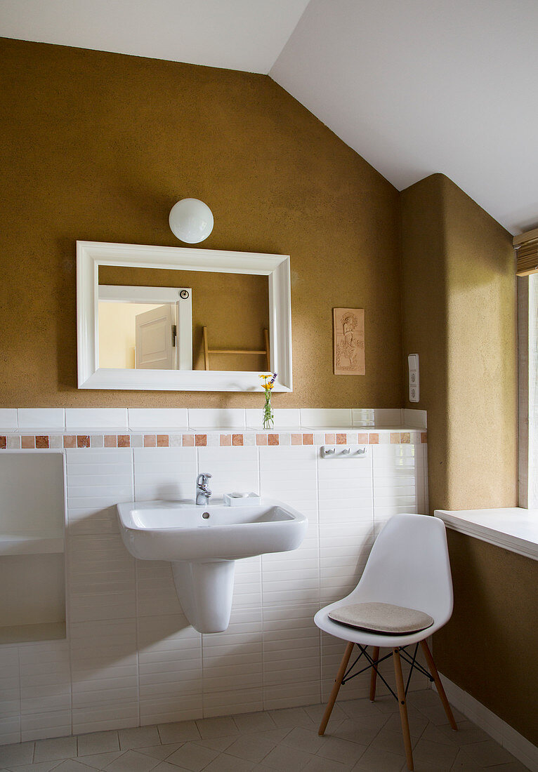 White chair next to sink in bathroom with cinnamon-brown wall