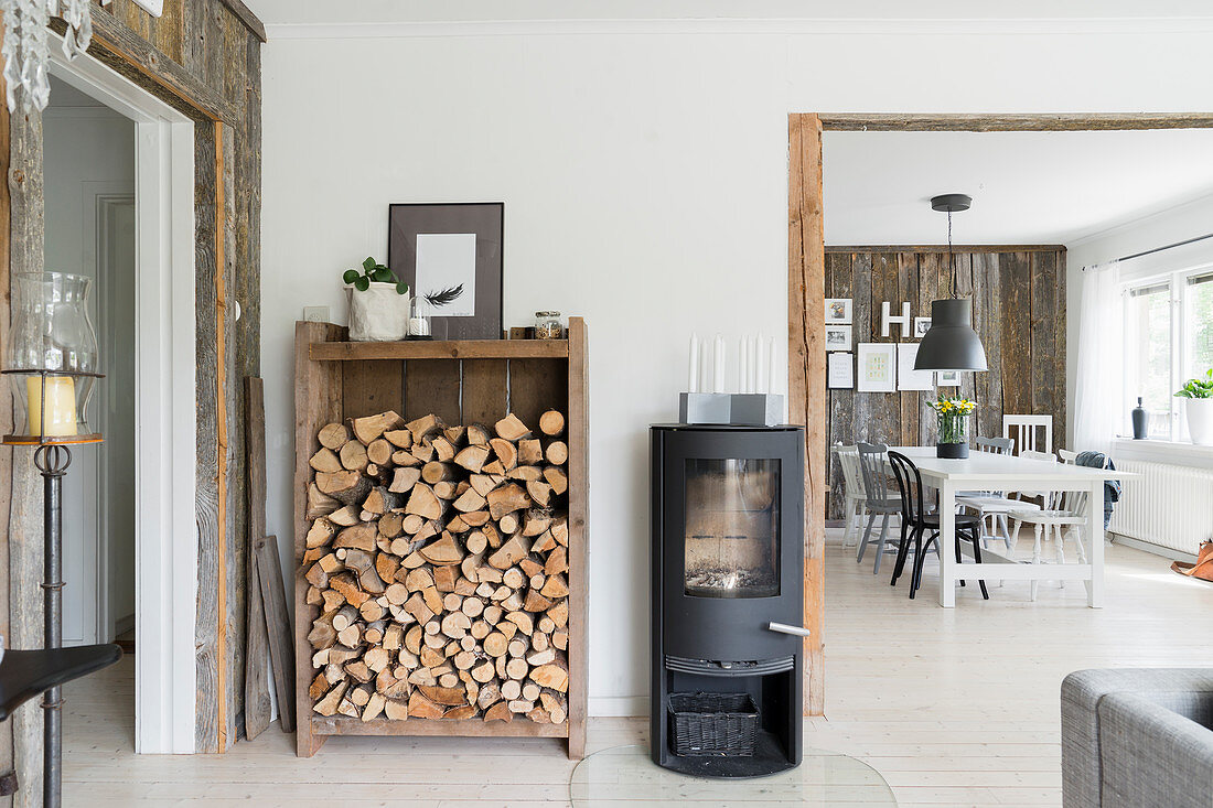 Firewood rack and wood-burning stove next to open doorway leading into dining room