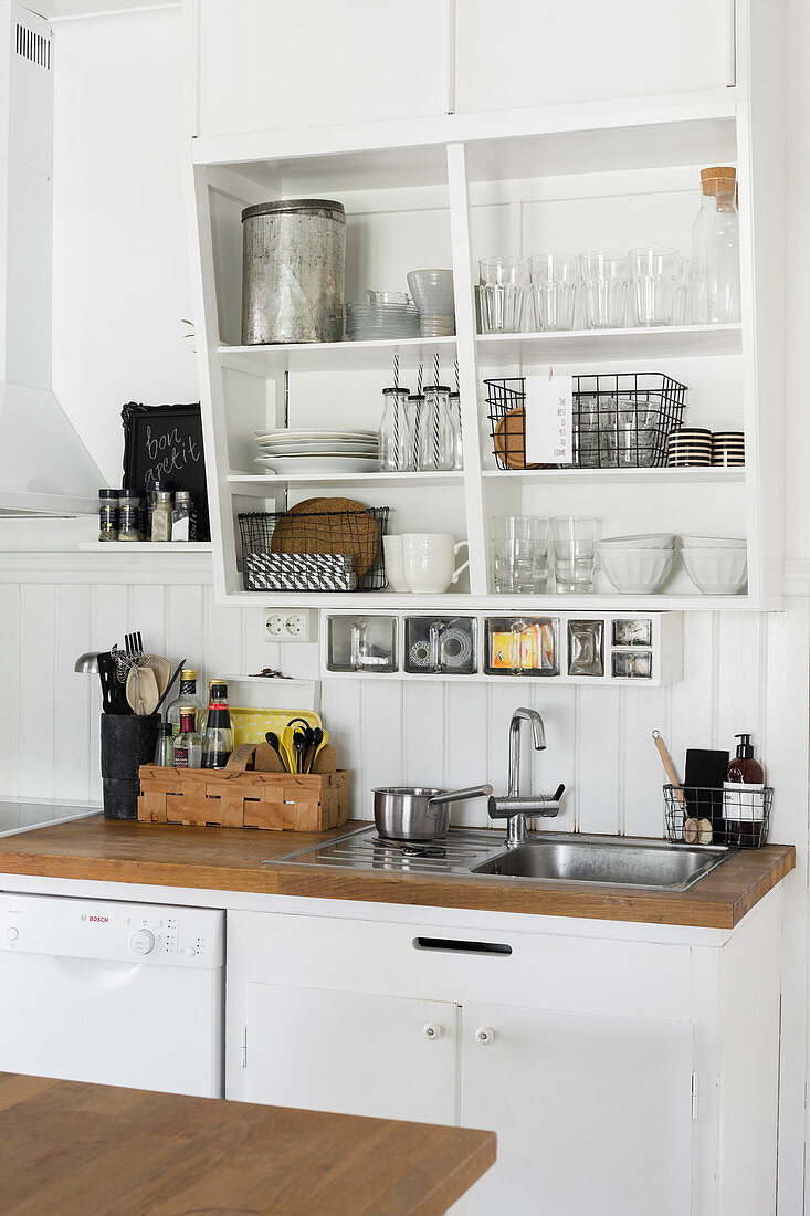 Crockery and glasses on slanted shelves above sink