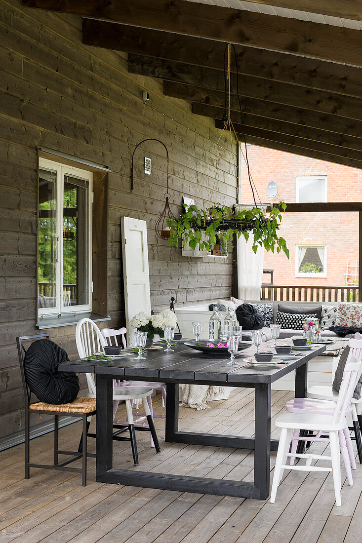 Gedeckter Esstisch auf der überdachten Terrasse am Holzhaus