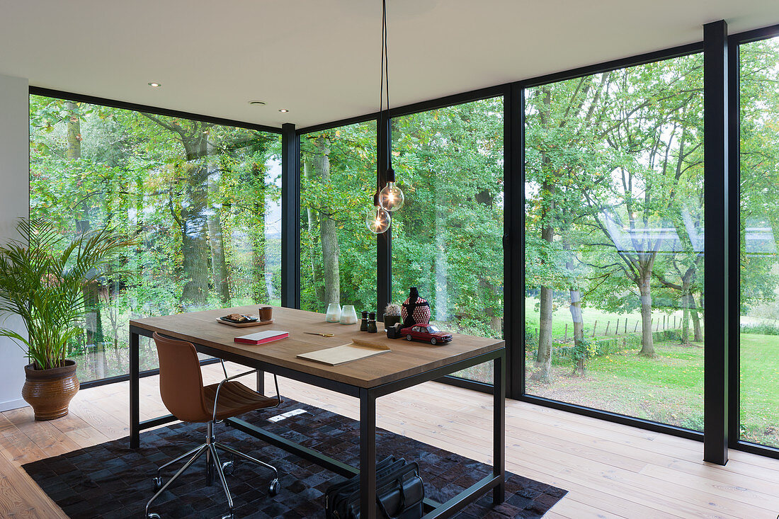 Desk opposite glass wall overlooking garden in architect-designed house