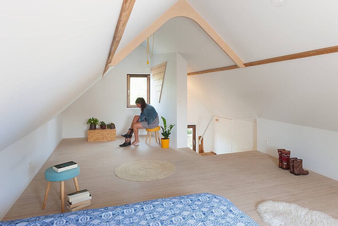 Attic room with exposed wooden beams, minimalist furnishings and sloping ceiling