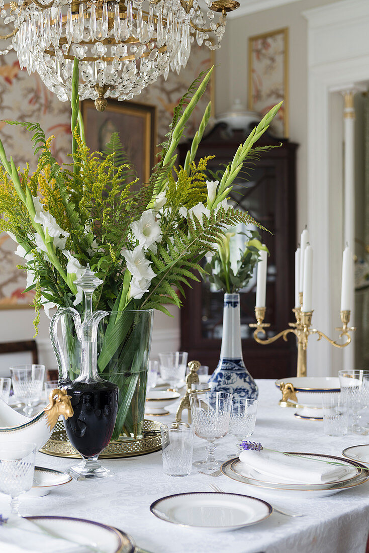 Strauß aus weißen Gladiolen, Farn und Goldrute auf gedecktem Tisch