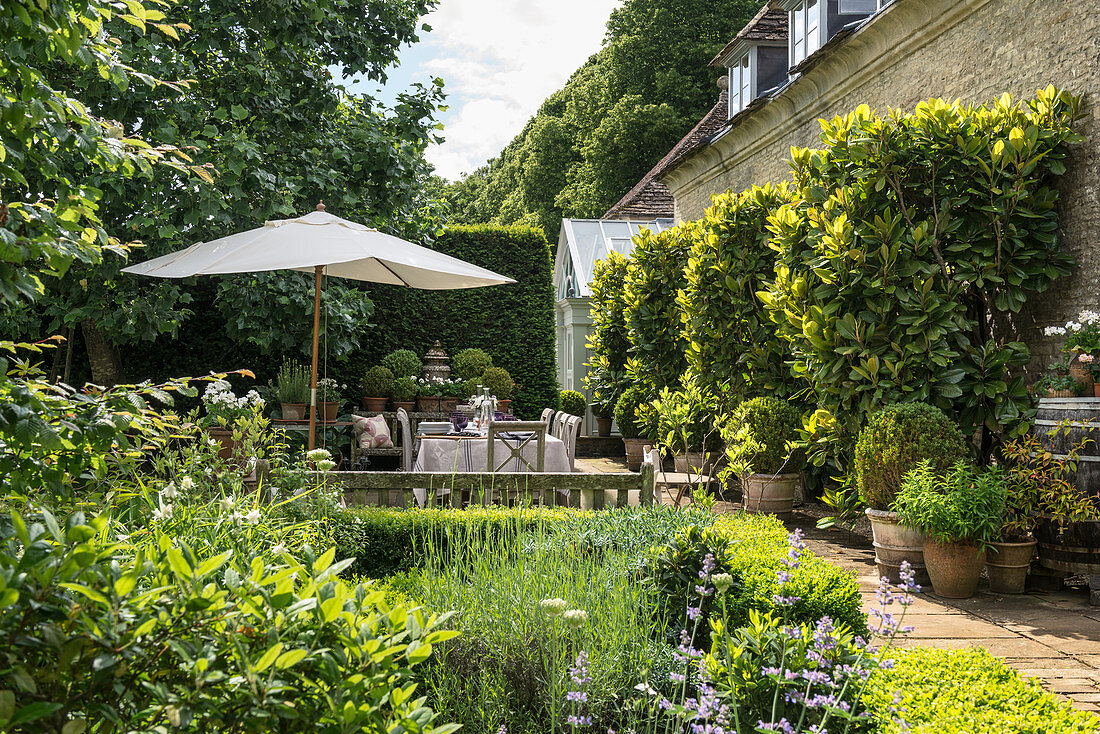 Summery, English-style garden with terrace adjoining stone house