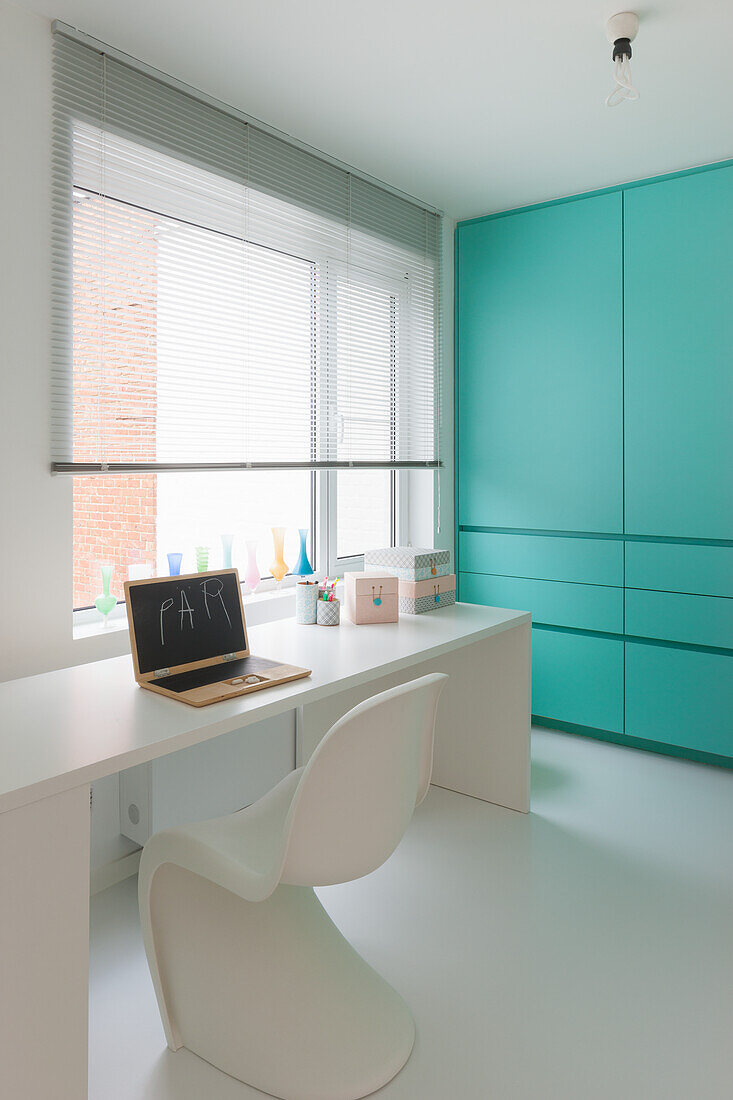 Simple work space with white desk and turquoise cupboard