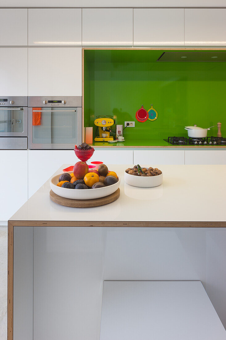 Modern kitchen with white cabinets and green backsplash