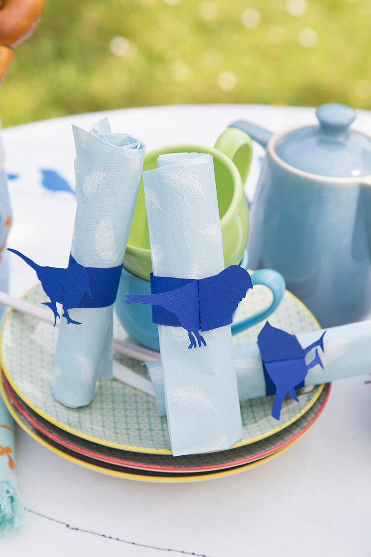DIY-Serviettenringe mit blauem Vogelmotiv auf sommerlichem Tisch im Garten
