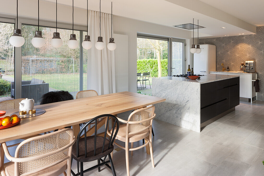 Open-plan kitchen with island, dining table, pendant lights and view of the yard