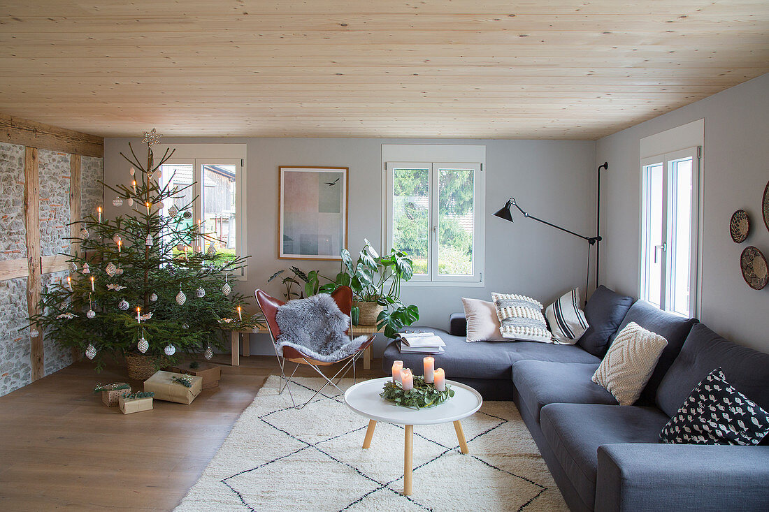 Grey corner sofa and Christmas tree in rustic living room