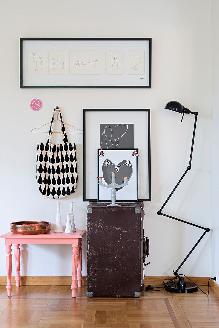 Decorative still-life arrangement of pink stool, old trunk and jointed standard lamp