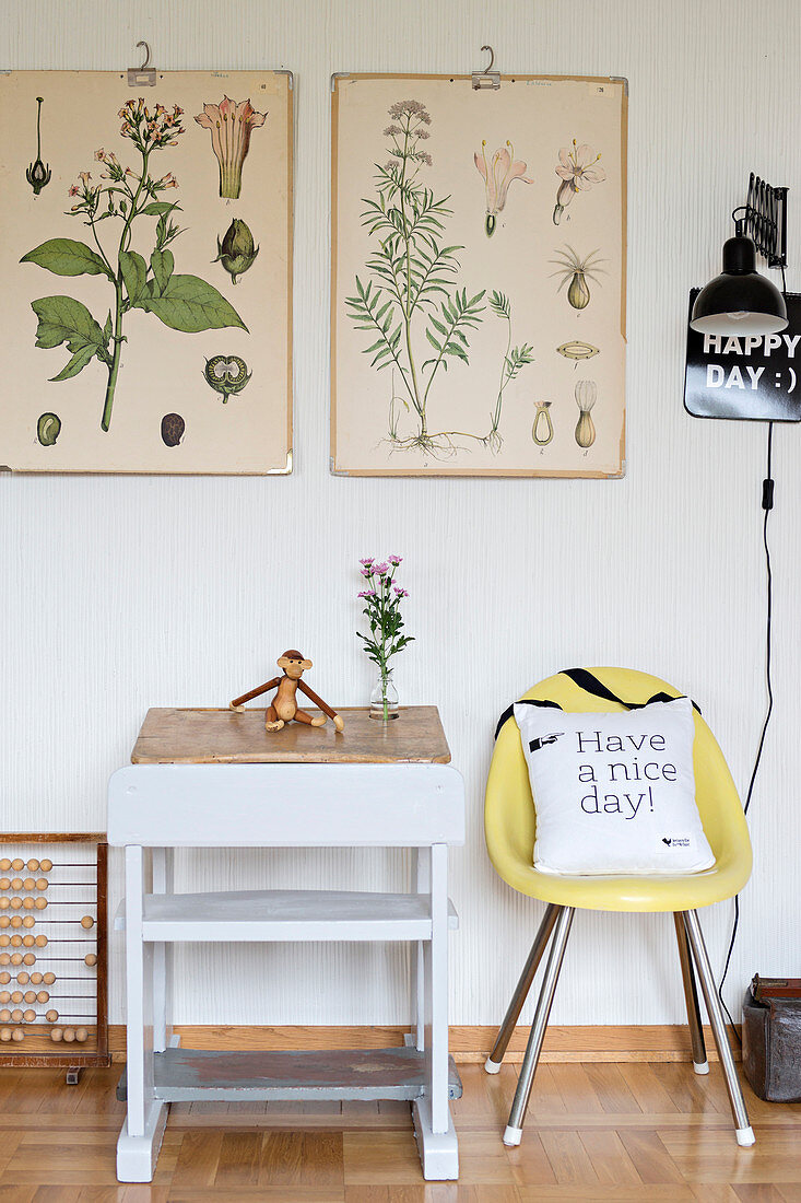 Botanical illustrations above old school desk and yellow chair