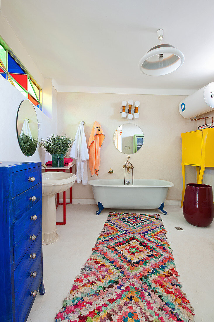 Free-standing bathtub and colourful accessories in large bathroom