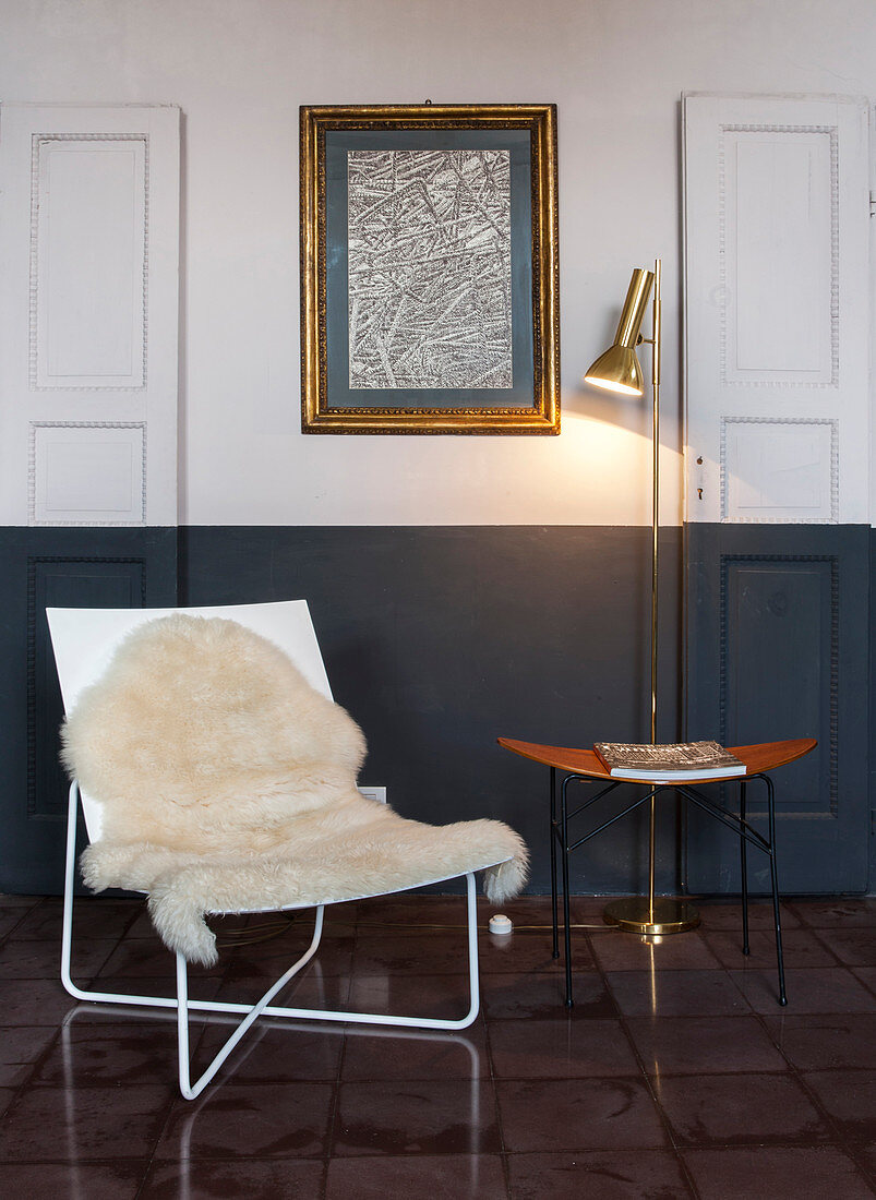 Sessel mit Tierfell, Beistelltisch und Stehlampe vor Wand mit Zeichnung