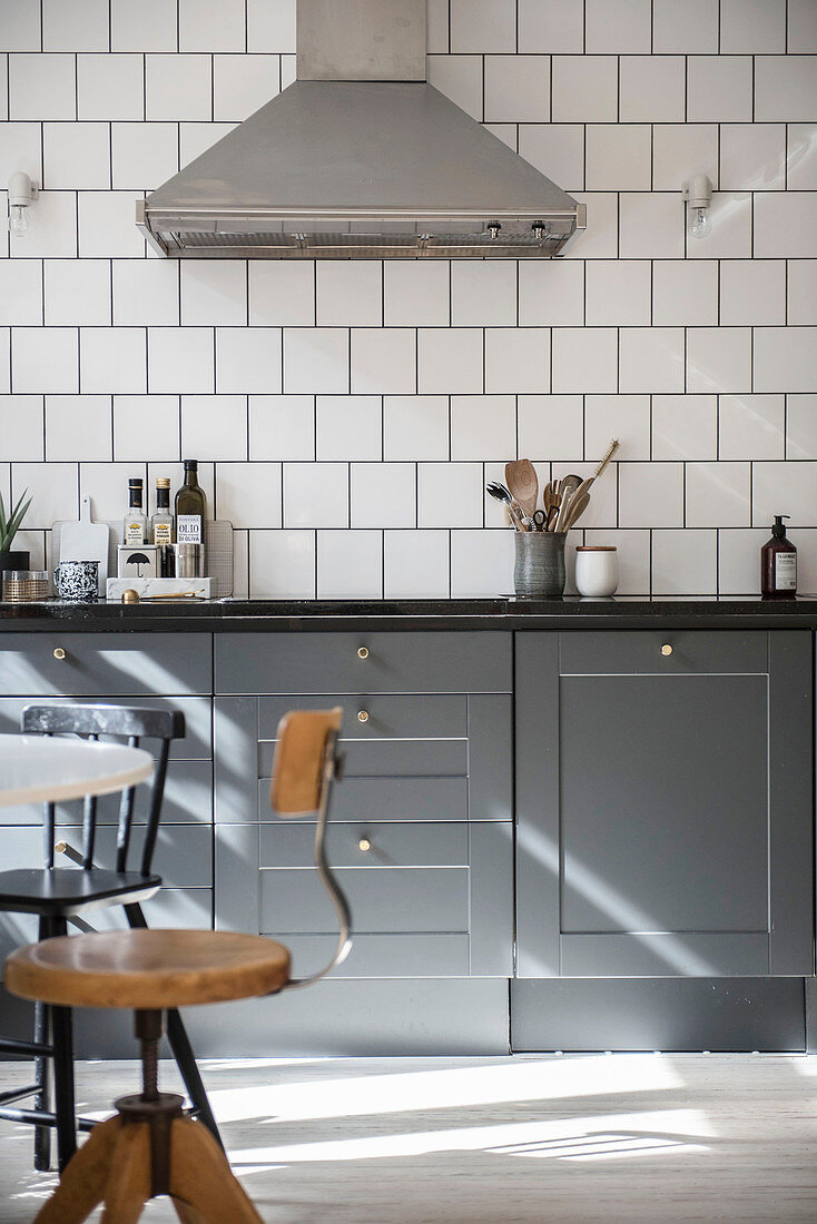 Grey cabinets and white square wall tiles in classic kitchen