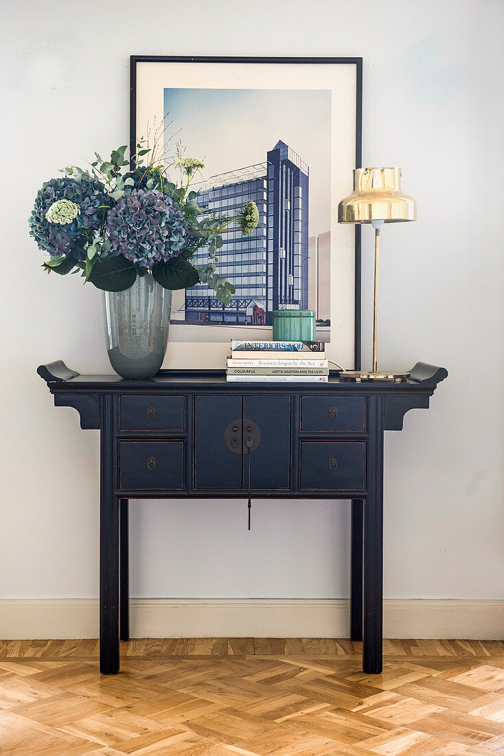 Vase of hydrangeas and picture on Oriental console table