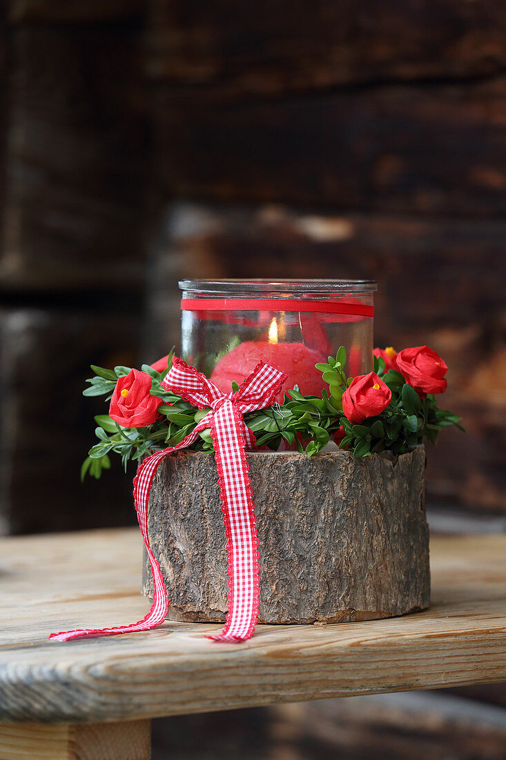 Candle lantern on stump decorated with handmade crepe flowers