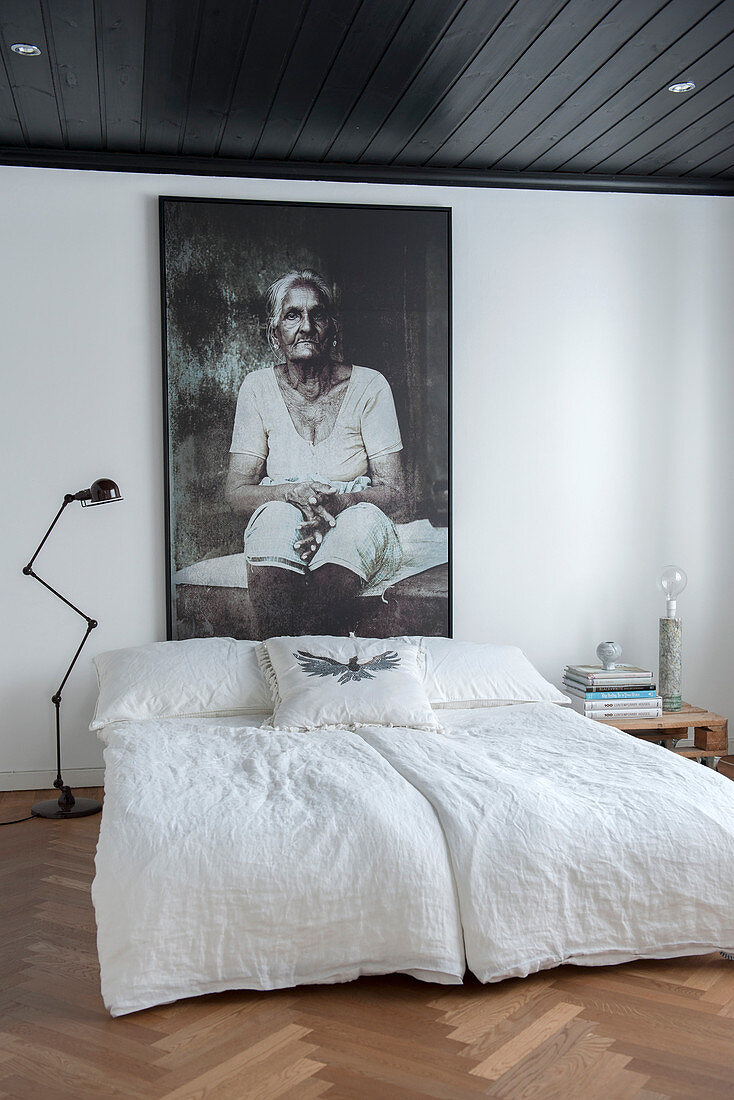 Portrait of old woman above bed in bedroom with parquet floor and black ceiling