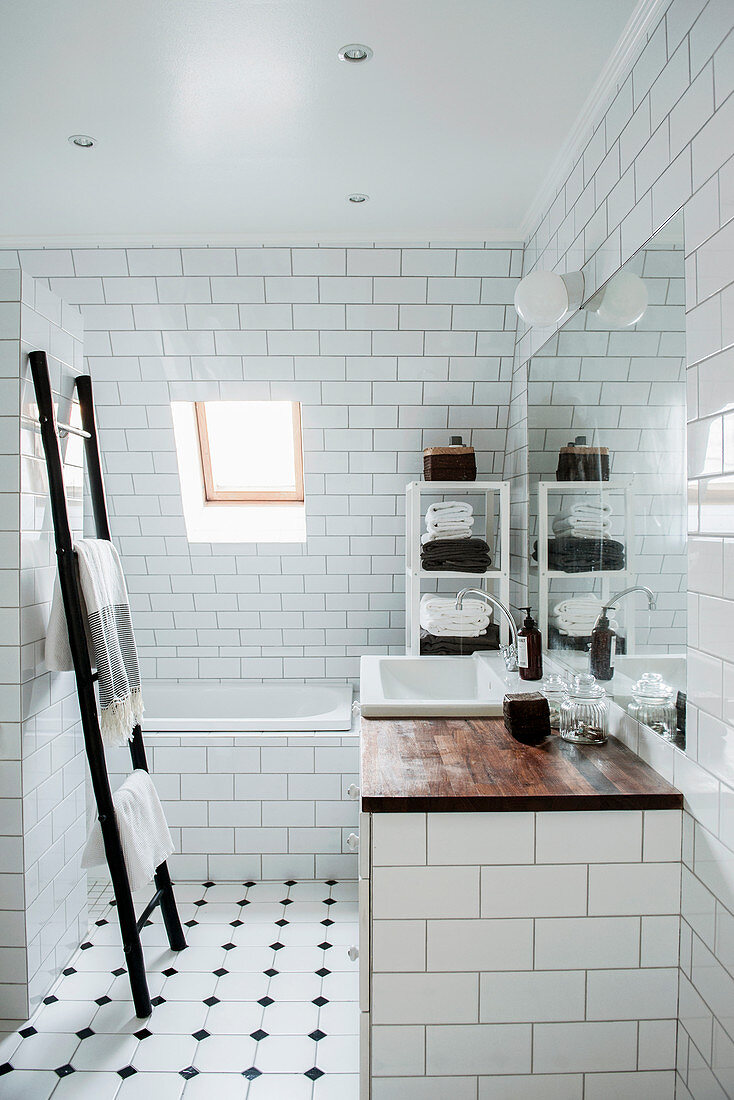 Ladder towel rack and bathtub in classic, attic bathroom with sloping wall
