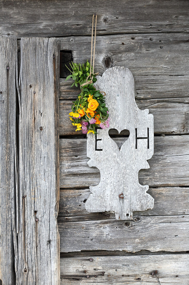Posy of real and paper flowers above rustic wooden door